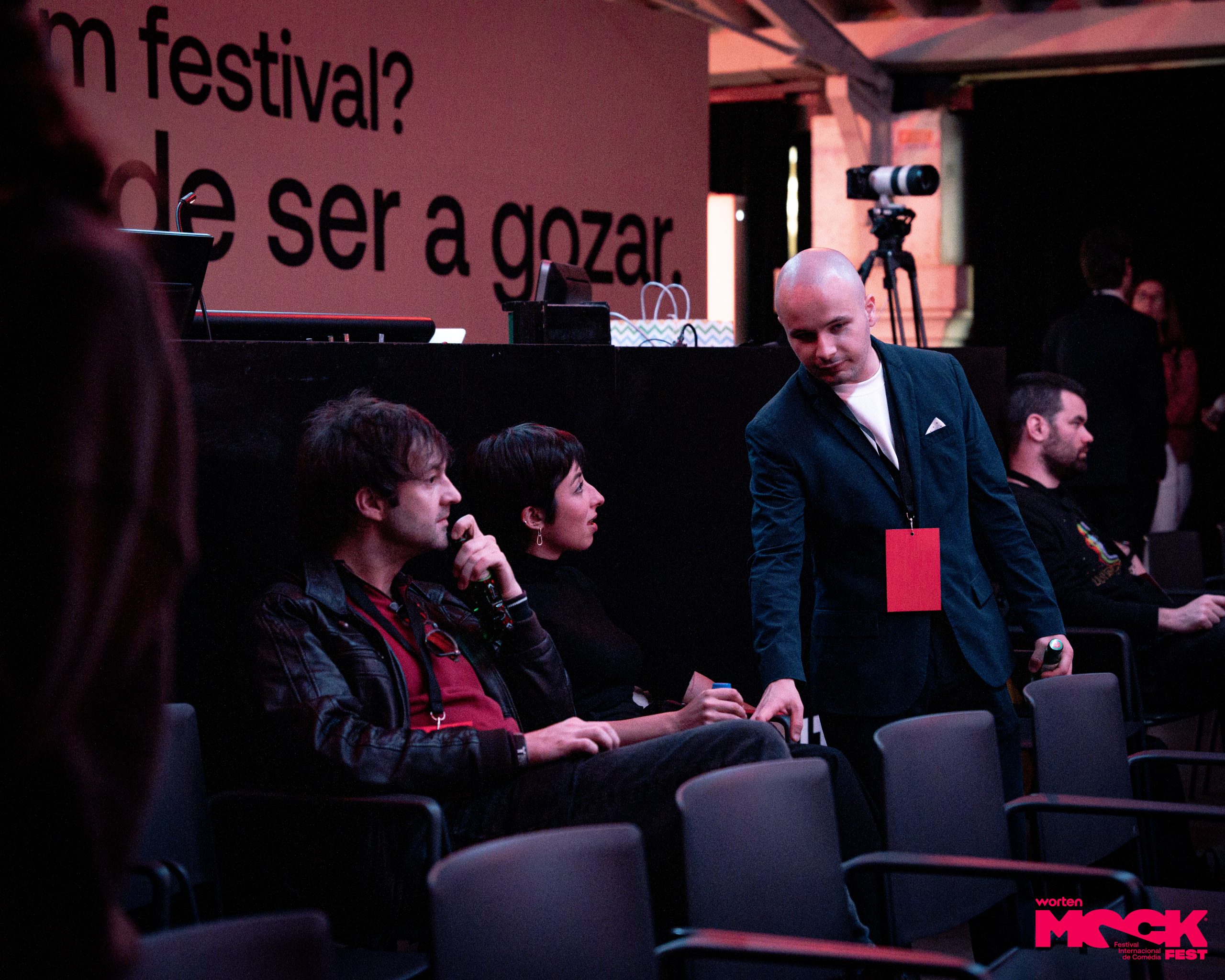 Participantes conversam e interagem no auditório do Worten Mock Fest, destacando o ambiente descontraído do festival de comédia.