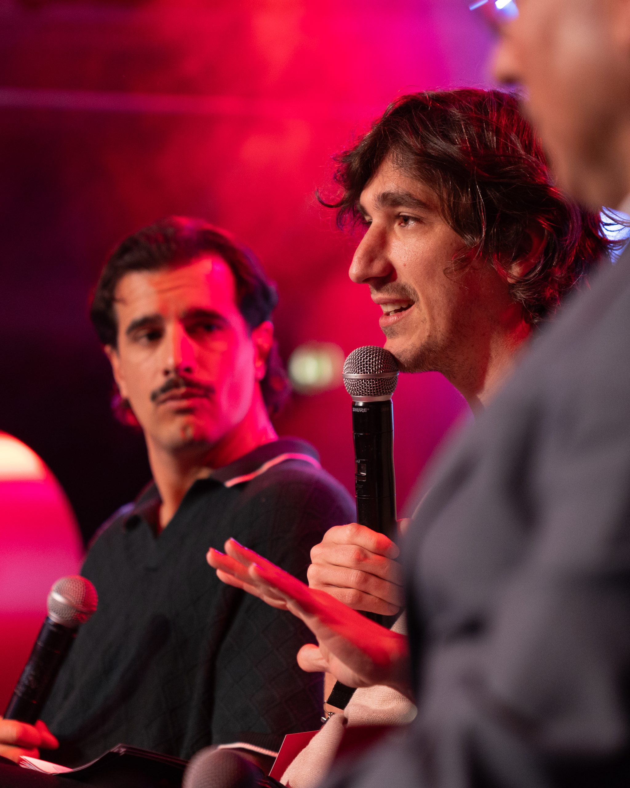 Comediantes no palco do Worten Mock Fest em um painel animado, sorrindo e conversando diante de uma plateia.