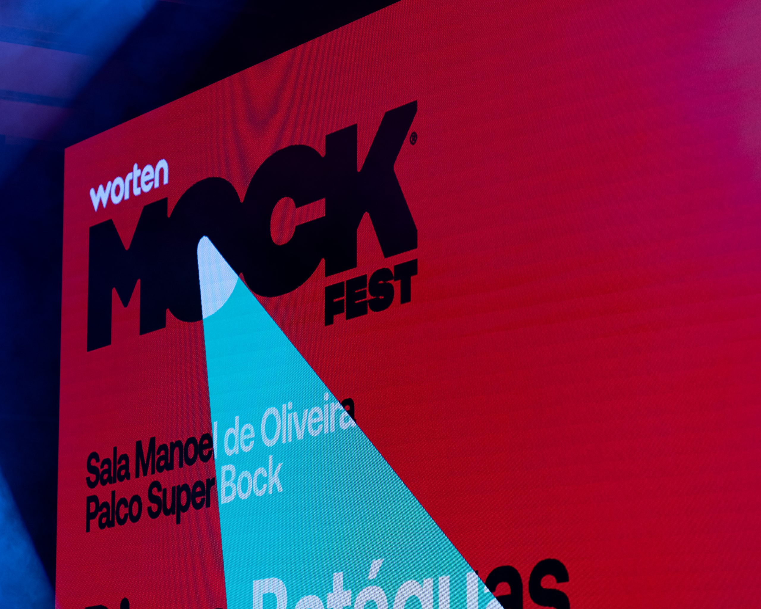 Ecrã LED do Worten Mock Fest destacando o logótipo do festival, o nome da sala Manoel de Oliveira e Palco Super Bock, com iluminação colorida de palco.