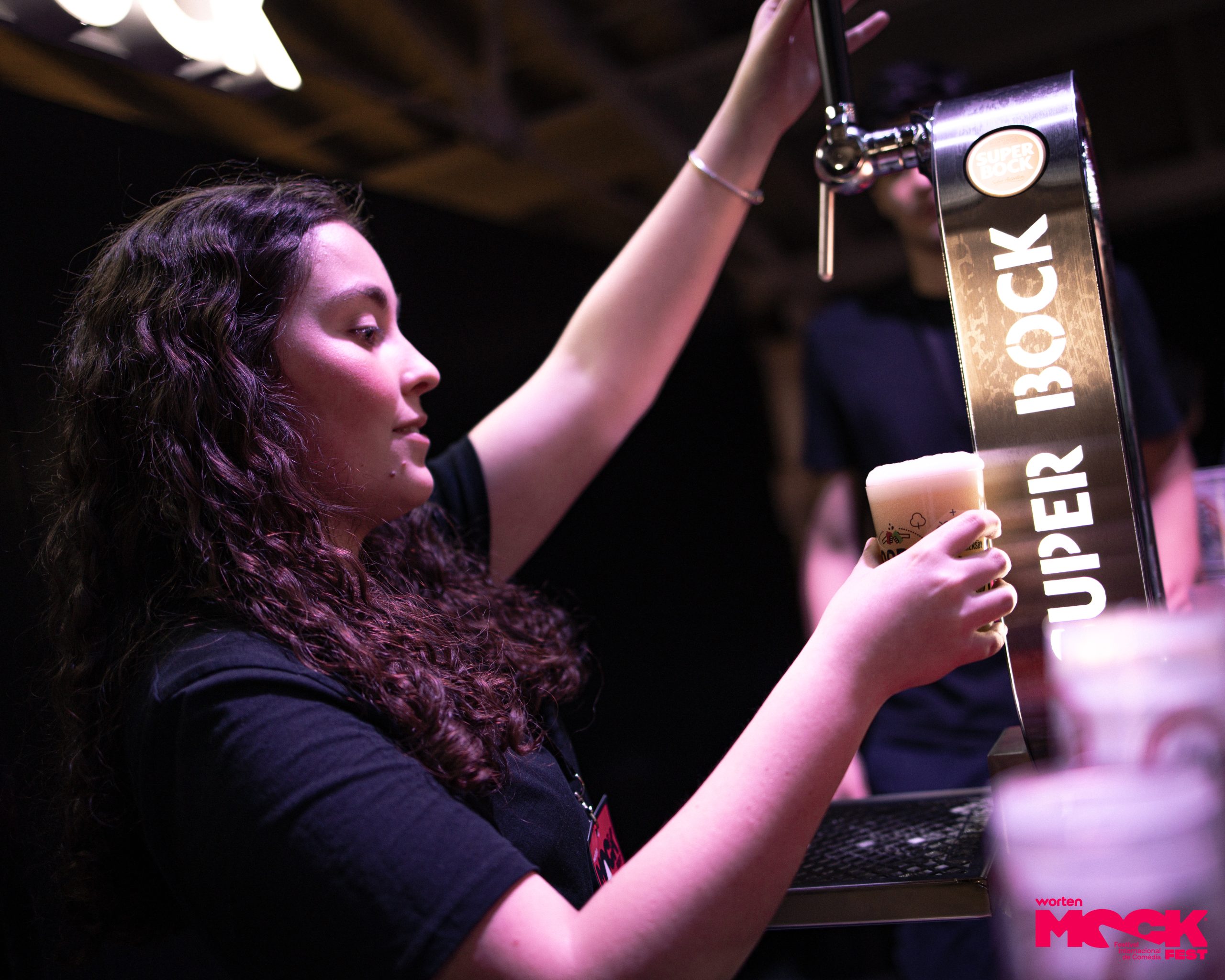 Funcionária do Mock Fest servindo cerveja da torneira Super Bock em um copo plástico durante o evento.